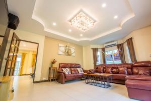 una sala de estar con muebles de cuero marrón y una lámpara de araña. en Baan Big Family Pool Villa, en Hua Hin
