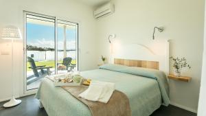 a white bedroom with a bed and a balcony at Sardegna é - Villa Charme&Design in Olbia