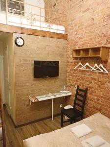 Cette chambre dispose d'un mur en briques, d'un bureau et d'une télévision. dans l'établissement Antre Hotel, à Saint-Pétersbourg