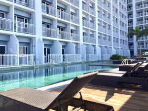 a swimming pool with a chair in front of a building at Sea Breeze Studio Manila in Manila