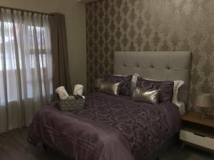 a bedroom with a large bed with purple sheets and pillows at AYA LUXURY APARTMENTS 78 in Durban +25 photos