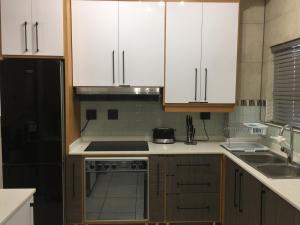 a kitchen with white cabinets and a stove top oven at AYA LUXURY APARTMENTS 78 in Durban