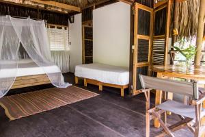 a bedroom with a bed and a desk and a table at Playa Pikua Ecolodge in Guachaca