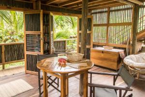 a room with a table and chairs on a porch at Playa Pikua Ecolodge in Guachaca