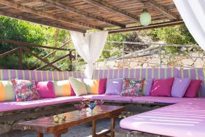 a purple couch with colorful pillows and a table at Amalia Villas in Nydri
