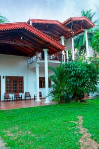 a large white house with a patio with a roof at Kolition Villa in Dickwella