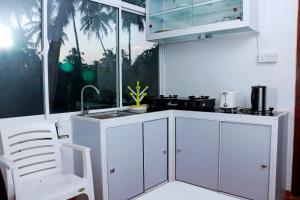 a white kitchen with a sink and a window at Kolition Villa in Dickwella