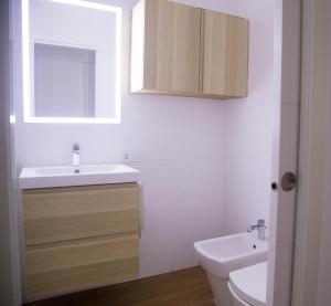 W łazience znajduje się umywalka, toaleta i lustro. w obiekcie Las Palmas BEACH w mieście Las Palmas de Gran Canaria