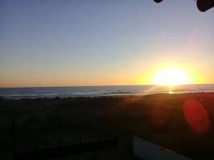 a sunset on the beach with the sun setting at Ñande Roga San Cemente in San Clemente del Tuyú