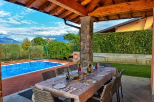 a dining table with chairs and a pool in the background at Villa Artemia in Manerba del Garda