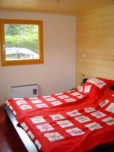 a bedroom with a red and white bed with a window at Chalet Notre Retraite in Ventron