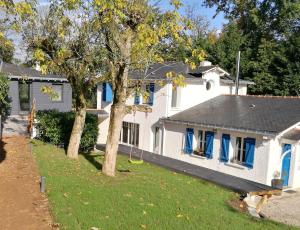 uma casa branca com janelas azuis e um quintal em Le Nid de l'Erdre em Sucé