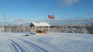 a gazebo with a red flag in the snow at Brīvdienu māja 1 in Kurmēni