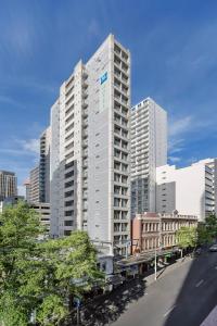 um edifício de apartamentos branco e alto numa cidade em ibis budget Auckland Central em Auckland