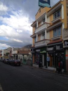 a building on a city street with cars parked at Samana Hostal in Otavalo