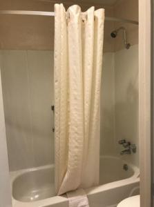 La salle de bains est pourvue d'un rideau de douche blanc à côté d'une baignoire. dans l'établissement Americas Best Value Inn Mount Vernon, à Mount Vernon