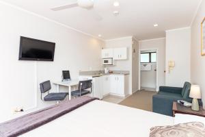 a bedroom with a bed and a living room with a kitchen at Outrigger Motel in Paihia