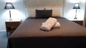 - un lit avec une serviette blanche et 2 lampes dans l'établissement Verandah Motel, à Gympie