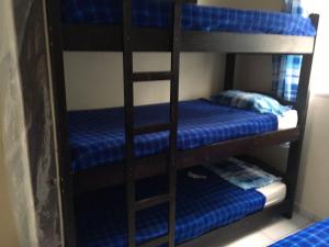 two bunk beds in a room with blue sheets at Edifício Malibú in Praia Grande