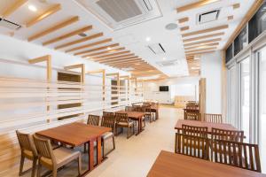 uma sala de jantar com mesas e cadeiras de madeira em Hotel Higashimokoto em Abashiri