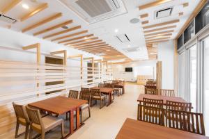 a dining room with wooden tables and chairs at Hotel Higashimokoto in Abashiri