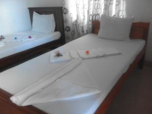 two beds with white sheets and white towels on them at Sihilro Regency in Udawalawe