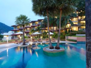 a swimming pool with palm trees in front of a hotel at Chanalai Flora Resort, Kata Beach in Kata Beach