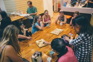 un grupo de personas sentadas alrededor de una mesa de madera en Melbourne City Backpackers, en Melbourne