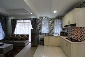 a kitchen and living room with a couch in it at Diyar Villas Puncak M6-11 in Puncak