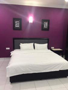 a bedroom with a large bed with a purple wall at ARA Muslim House @ Mutiara Heights Johor Bahru in Johor Bahru