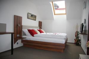 a bedroom with a bed with white sheets and red pillows at Art Hotel Podebrady in Poděbrady