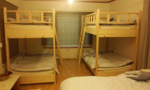 a room with three bunk beds in a room at Geoje Ton Ton Guesthouse in Geoje 