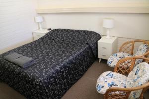a bedroom with a bed and two chairs at Renmark Motor Inn in Renmark
