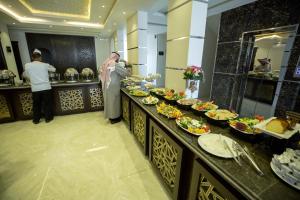 um homem parado em frente a um buffet de comida em Rest Night Hotel Apartments Wadi Al Dawasir em Wadi Al Dawasir