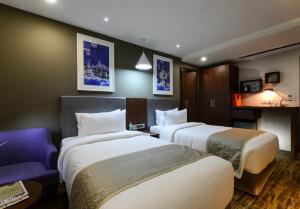 a hotel room with two beds and a purple couch at Howard Johnson by Wyndham, Kolkata Airport in Kolkata