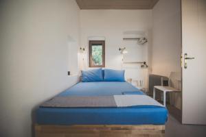 a blue bed in a white room with a window at Donusa Beach House - Etheras properties in Diakofti