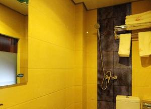 uma casa de banho amarela com um chuveiro e um WC em JUNYI Hotel Guizhou Guiyang Bageyan Road em Guiyang