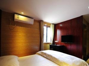 a bedroom with two beds and a tv on the wall at JUNYI Hotel Guizhou Guiyang Bageyan Road in Guiyang