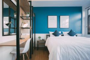 a bedroom with blue walls and a bed and a desk at Baan Noppadol in Bangkok