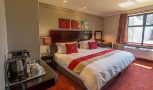 a hotel room with a large bed with red pillows at Peermont Metcourt Inn at the Grand Palm, Gaborone in Gaborone