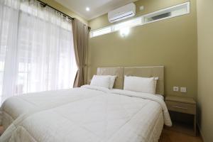 a bedroom with a large white bed with a window at Diyar Villas Puncak M6/12 in Puncak