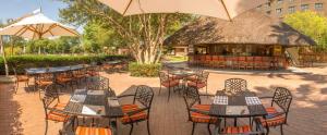un patio extérieur avec des tables et des chaises ainsi qu'un restaurant dans l'établissement Peermont Metcourt Inn at the Grand Palm, Gaborone, à Gaborone