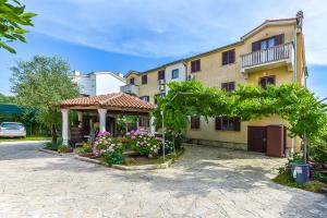 a house with a gazebo and flowers in a yard at Apartments Adria in Biograd na Moru