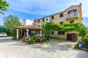a house with a gazebo and flowers in a yard at Apartments Adria in Biograd na Moru