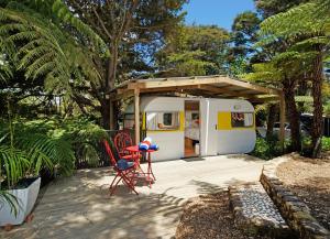 a rv with chairs and a table and a porch at Wai-knot Accommodation in Onetangi