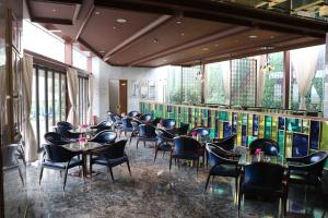 a dining room with tables and chairs and windows at Rongjiang Hotel in Jieyang