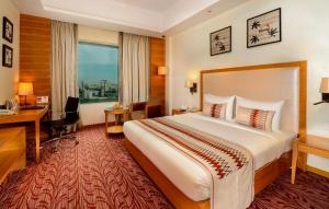 a hotel room with a large bed and a desk at Pride Plaza Hotel, Kolkata in Kolkata