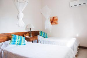 Pokój z 2 łóżkami i stołem z lampką w obiekcie Coconuts w mieście Grand Baie