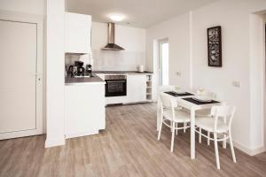 プラヤ・オンダにあるFlower Beach Suite 7の白いキャビネット、テーブルと椅子付きのキッチンが備わります。