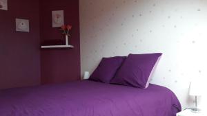 Lampaul-PlouarzelにあるVilla Lampaulの白い壁の紫色のベッドが備わるベッドルーム1室が備わります。